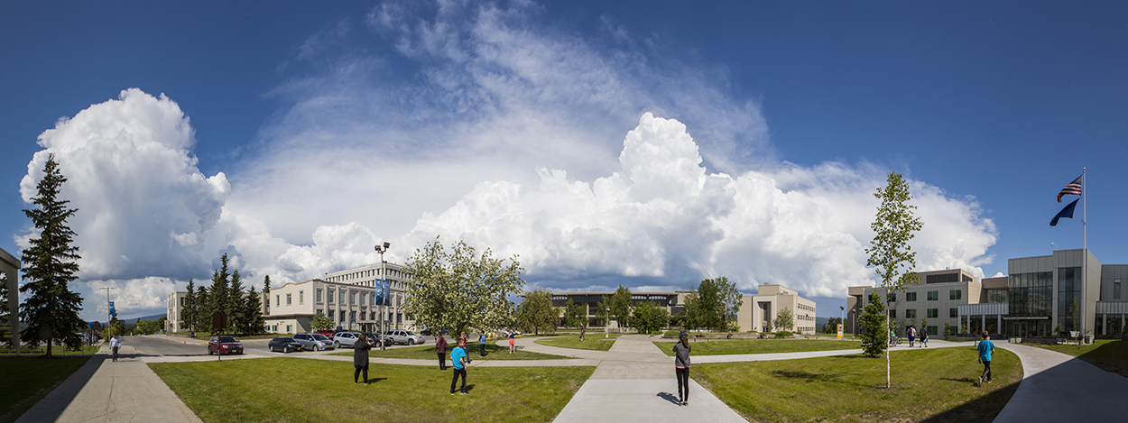 Panoramic view of students walking through Cornerstone Plaza on the Fairbanks campus in summer
